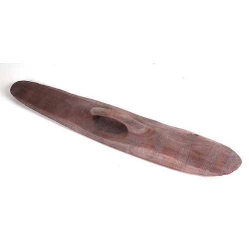 131 - An Australian Aboriginal wooden shield with incised decoration to front and rear, 75cms long.