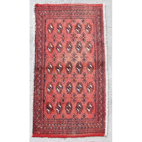 181 - A small Persian Turkoman rug with repeated guls on a red ground, 128 by 58cms.