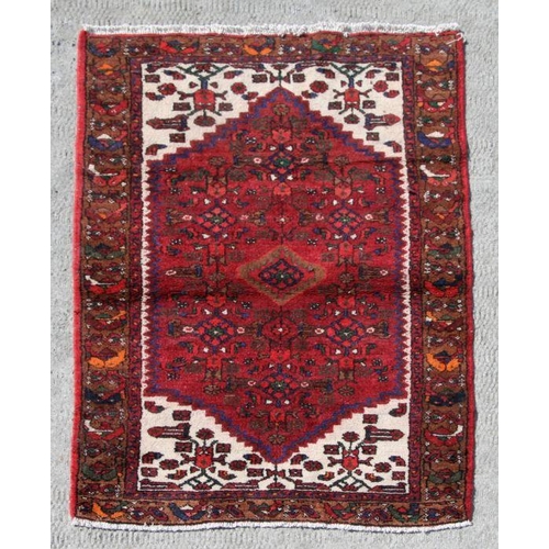 183 - A Persian Hamadan hand knotted woollen rug with stylised design within borders, on a red ground, 140... 