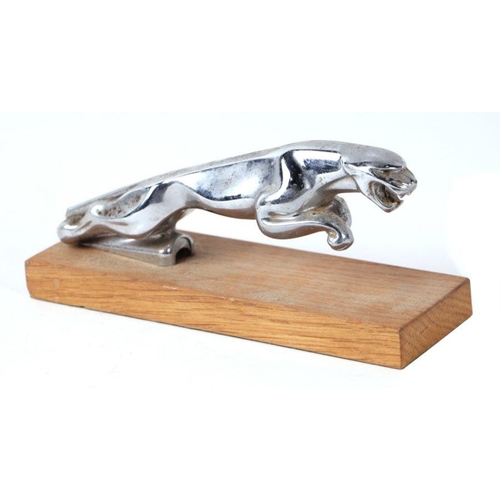 114 - A Jaguar car mascot mounted on a wooden plinth, 18cms long.