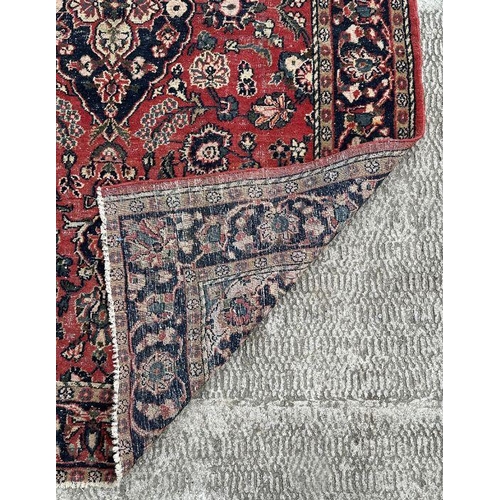 270 - A Persian rug with central blue medallion on a red ground with floral motifs within a floral multi b... 