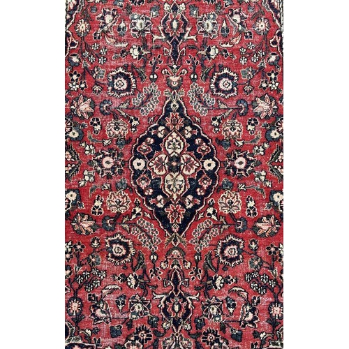 270 - A Persian rug with central blue medallion on a red ground with floral motifs within a floral multi b... 