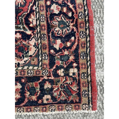 270 - A Persian rug with central blue medallion on a red ground with floral motifs within a floral multi b... 