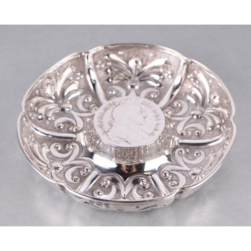 576 - A silver scalloped dish with embossed decoration and raised coin set centre, London 1895 and maker's... 