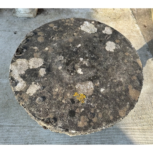 6 - A reconstituted stone bird table with circular top, on a cast cherub form support, 50cms dimeter.