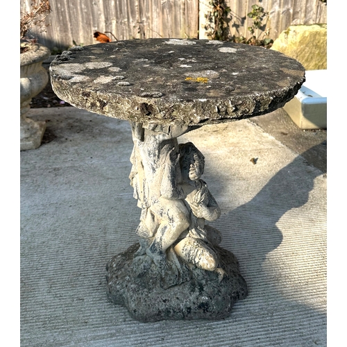 6 - A reconstituted stone bird table with circular top, on a cast cherub form support, 50cms dimeter.