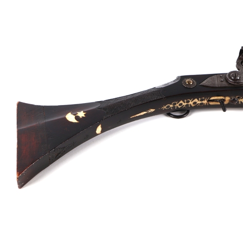 103 - A 19th century North African flintlock long gun, the lock and barrel signed and the stock with inlai... 