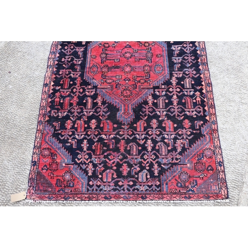 287 - A Persian hand knotted rug with stylised design, on a blue ground, 183 by 110cms (68).