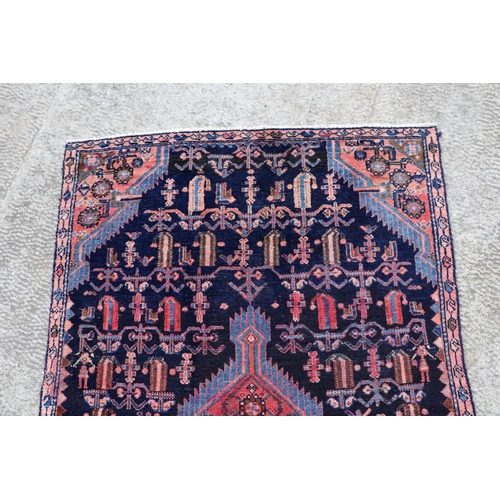 287 - A Persian hand knotted rug with stylised design, on a blue ground, 183 by 110cms (68).