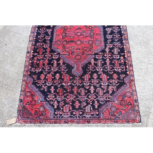 141 - A Persian hand knotted rug with stylised design, on a blue ground, 183 by 110cms (68).