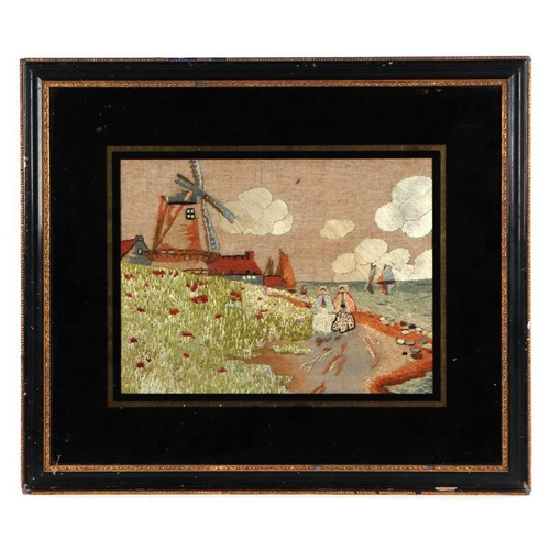 191 - An early 20th century Dutch needlework panel depicting figures on a coastal path with a windmill  in... 