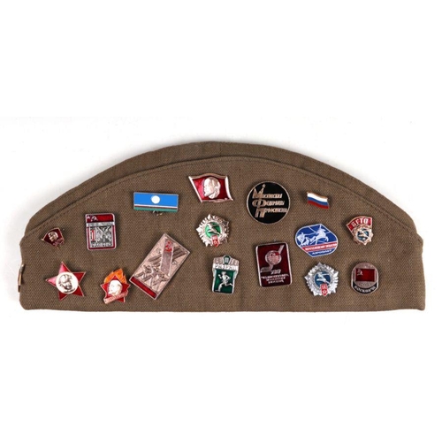 30 - A Russian military side cap with a quantity of Russian enamel badges.