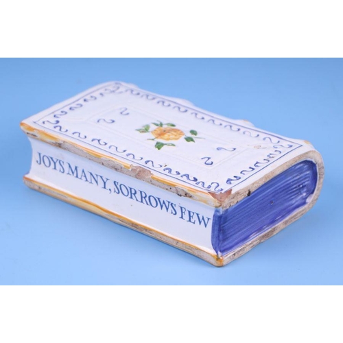 326 - An English Delft tin glaze handwarmer in the form of a book with moulded decoration, painted flowers... 