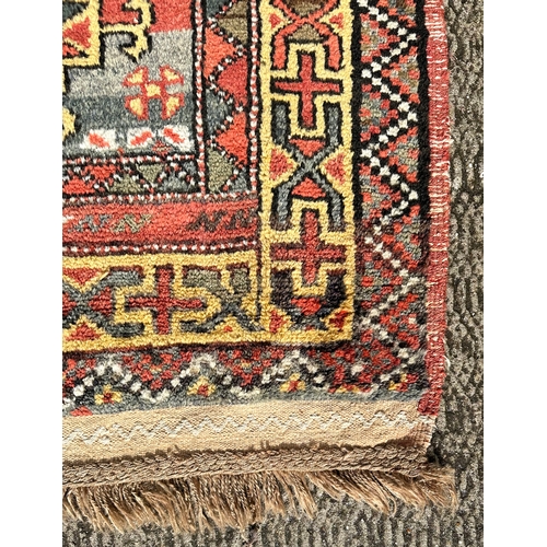 118 - A Northeast Persian Quchan Kurdish rug with central repeating medallions on a red ground within a mu... 