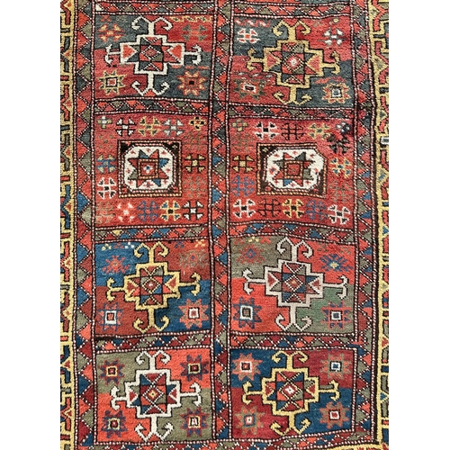 118 - A Northeast Persian Quchan Kurdish rug with central repeating medallions on a red ground within a mu... 