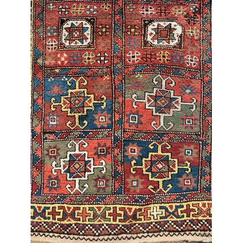 118 - A Northeast Persian Quchan Kurdish rug with central repeating medallions on a red ground within a mu... 