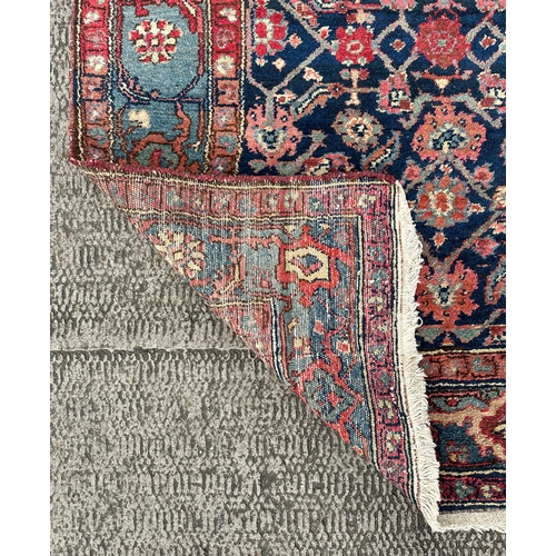 120 - A Northwest Persian Bijar rug with repeating floral motifs on a dark blue ground within a multi bord... 