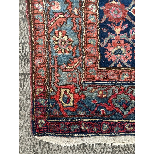 120 - A Northwest Persian Bijar rug with repeating floral motifs on a dark blue ground within a multi bord... 