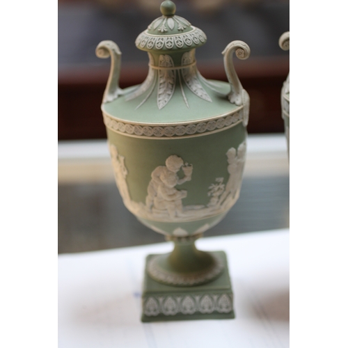 347 - A pair of Wedgwood green classical Jasperware urns and covers decorated with figures, 20cms high; to... 