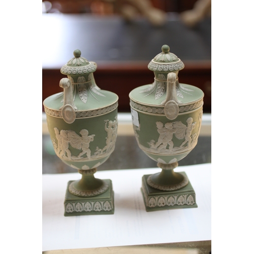 347 - A pair of Wedgwood green classical Jasperware urns and covers decorated with figures, 20cms high; to... 