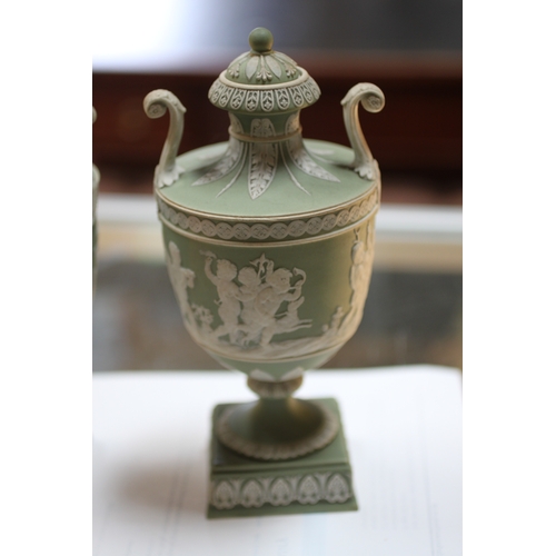 347 - A pair of Wedgwood green classical Jasperware urns and covers decorated with figures, 20cms high; to... 