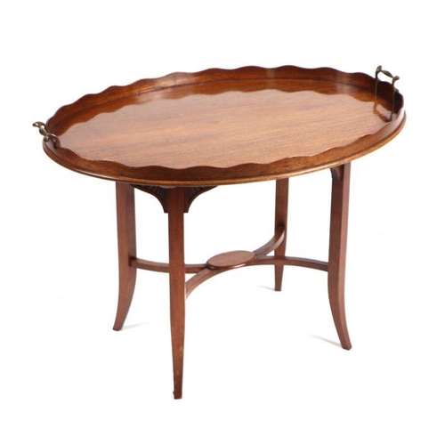 1052 - An Edwardian mahogany galleried oval two-handled tray mounted on an associated table base, 72cms wid... 