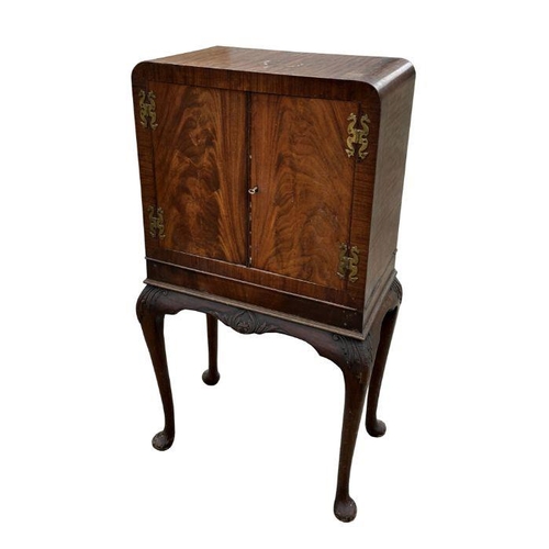 1061 - An early 20th century Queen Anne style mahogany drinks cabinet on stand, the pair of panelled doors ... 