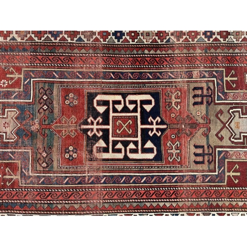 177 - A Persian hand knotted rug decorated with a geometric pattern on a red ground, 124 by 241cms.