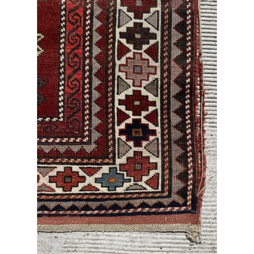 177 - A Persian hand knotted rug decorated with a geometric pattern on a red ground, 124 by 241cms.