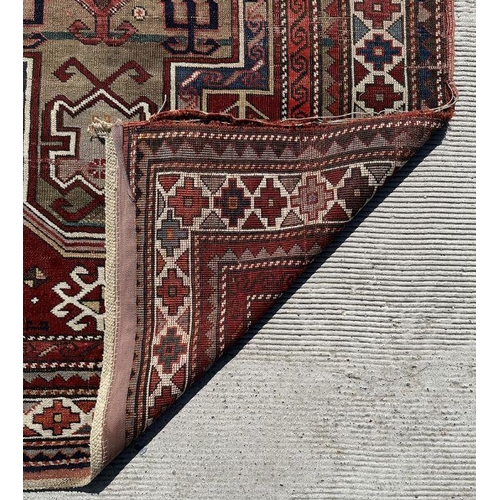 177 - A Persian hand knotted rug decorated with a geometric pattern on a red ground, 124 by 241cms.