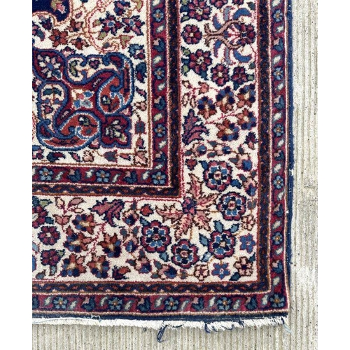 178 - A Persian rug with geometric floral design on a blue ground within a multi border, 130 by 210cms.