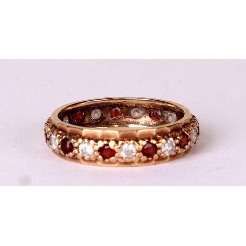 522 - A 9ct gold eternity ring set with white and red stones, approx UK size 'M', 2.6g.