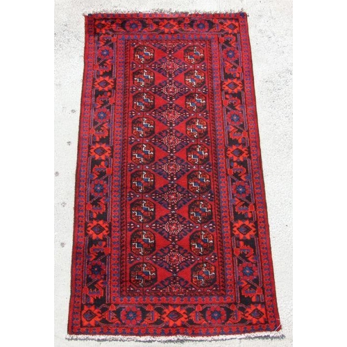 136 - A Persian Turkoman hand knotted runner with repeat geometric design, on a red ground, 230 by 117cms ... 