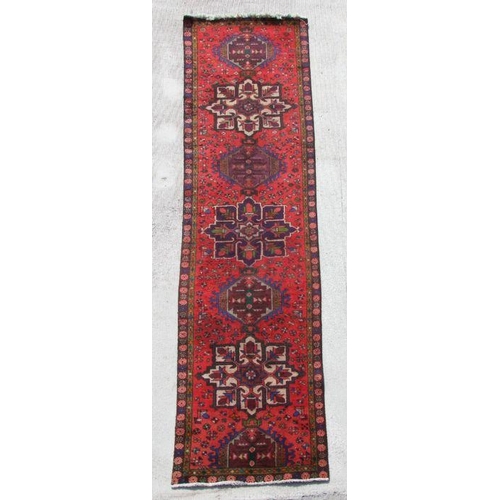 137 - A Persian hand knotted runner with repeat star design within floral borders, on a red ground, 380 by... 