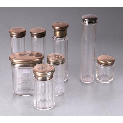 440 - A set of six George V silver topped glass cosmetics jars, initialled, London 1919 and other similar.