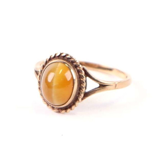 567 - A 9ct gold dress ring set with an oval tiger's eye cabochon, approx UK size 'O', 2.3g.