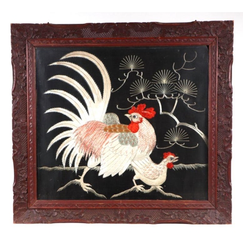 666 - A pair of Japanese embroidered panels depicting chickens, on a black ground, glazed and in ornate ca... 