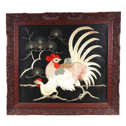 666 - A pair of Japanese embroidered panels depicting chickens, on a black ground, glazed and in ornate ca... 