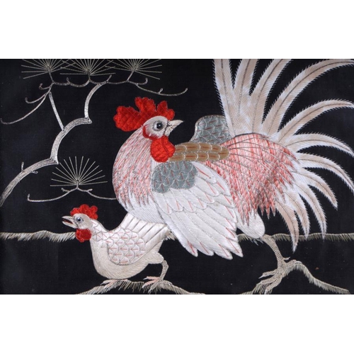 666 - A pair of Japanese embroidered panels depicting chickens, on a black ground, glazed and in ornate ca... 