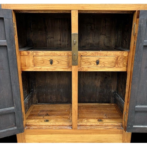 700 - A large Chinese pine cupboard of tapering form with a shelved interior, 110cms wide.