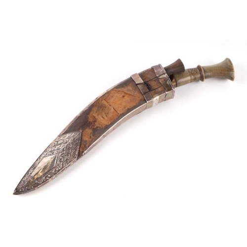 80 - A horn handled kukri in a wooden scabbard with white metal overlay decoration depicting an armorial ... 