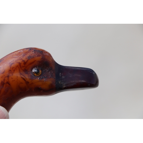 351 - An early plastic amber like walking stick handle in the form of a duck with a cherry amber Bakelite ... 