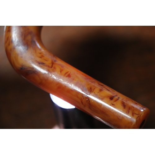 351 - An early plastic amber like walking stick handle in the form of a duck with a cherry amber Bakelite ... 