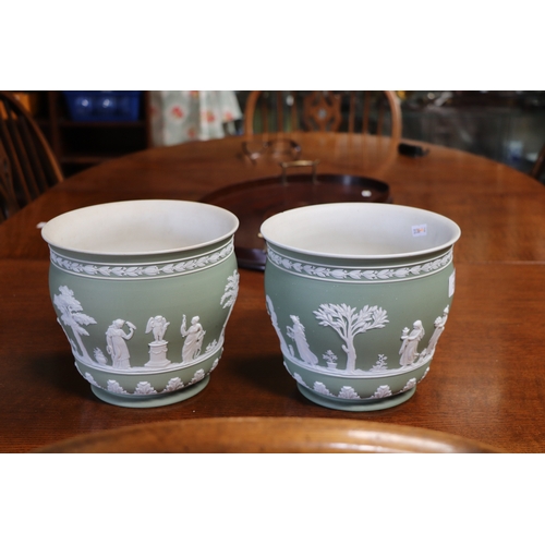 277 - A pair of Wedgwood Jasperware planters decorated with classical figures, 18cms high (2).