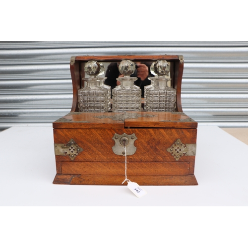 342 - A late 19th century oak three bottle Tantalus, the front section opening to reveal compartments cont... 