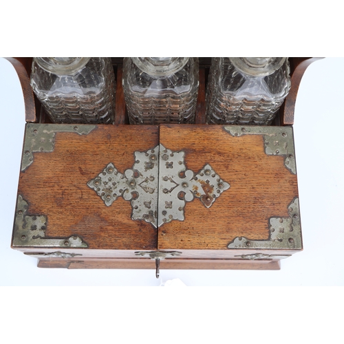 342 - A late 19th century oak three bottle Tantalus, the front section opening to reveal compartments cont... 