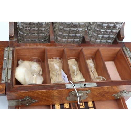 342 - A late 19th century oak three bottle Tantalus, the front section opening to reveal compartments cont... 