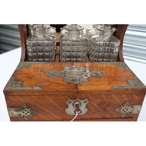 342 - A late 19th century oak three bottle Tantalus, the front section opening to reveal compartments cont... 