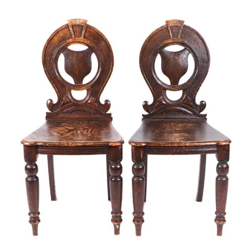 1004 - A pair of Victorian oak hall chairs with pierced horseshoe shaped backs (2).