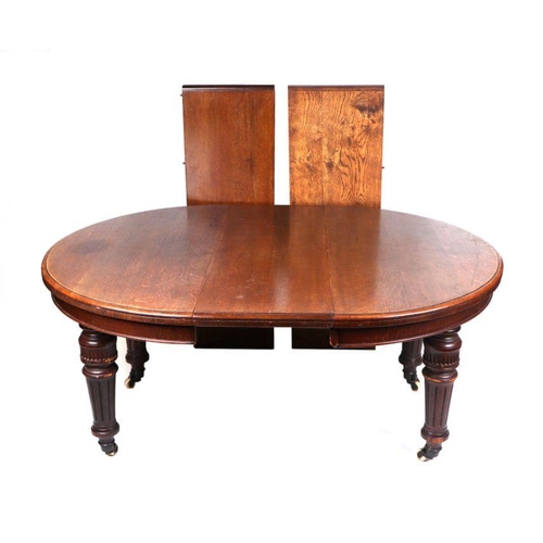 1015 - A late Victorian /  Early Edwardian oak dining table with demi-lune ends, tapering reeded legs, and ... 